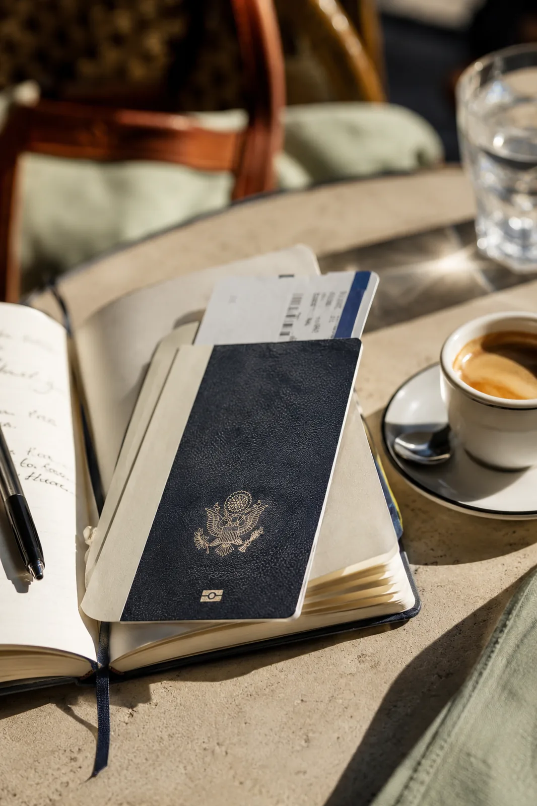 A sunlit cafe terrace abroad with an open journal, an espresso and a phone